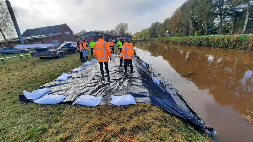 Folie met zandzakken in water en op kruin gefixeerd.